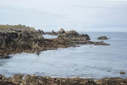 Fierce shore embracing steel blue sea